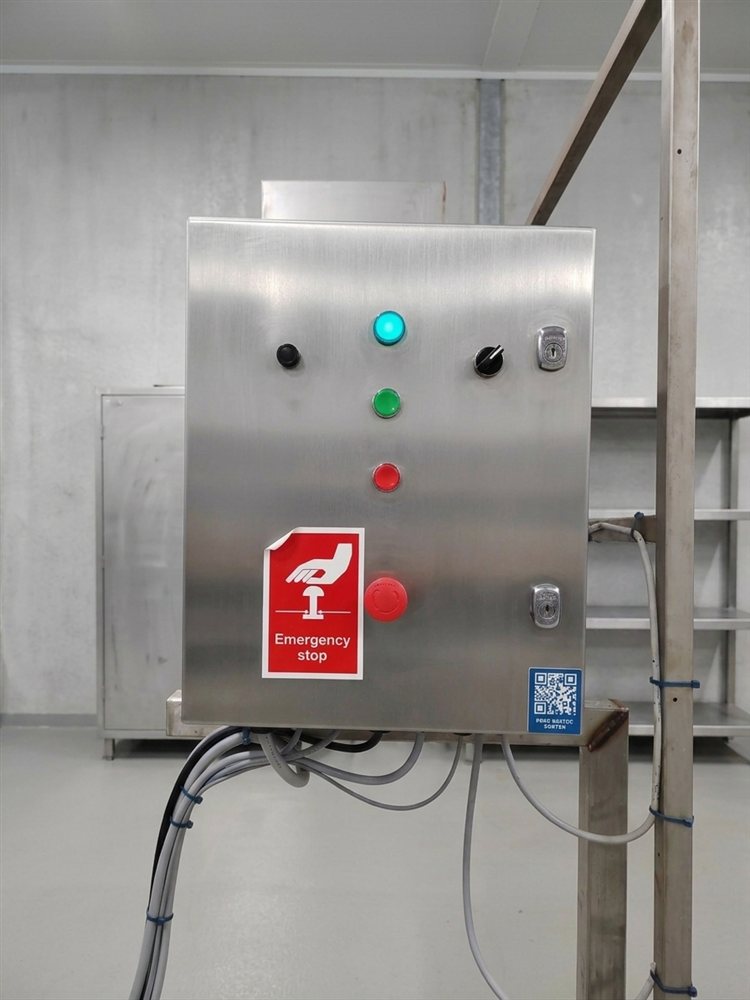 A QR code label fixed to a machine's control panel on the factory floor